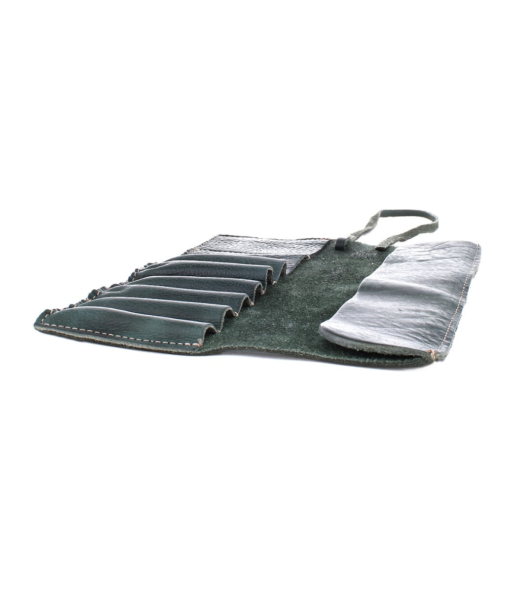 A dark green Prepped Leather Wrap from Bed Stu, featuring multiple slots, partially unrolled and empty, lies flat against a white background—the perfect companion for organizing your artist tools.