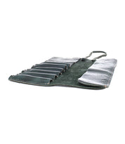 A dark green Prepped Leather Wrap from Bed Stu, featuring multiple slots, partially unrolled and empty, lies flat against a white background—the perfect companion for organizing your artist tools.