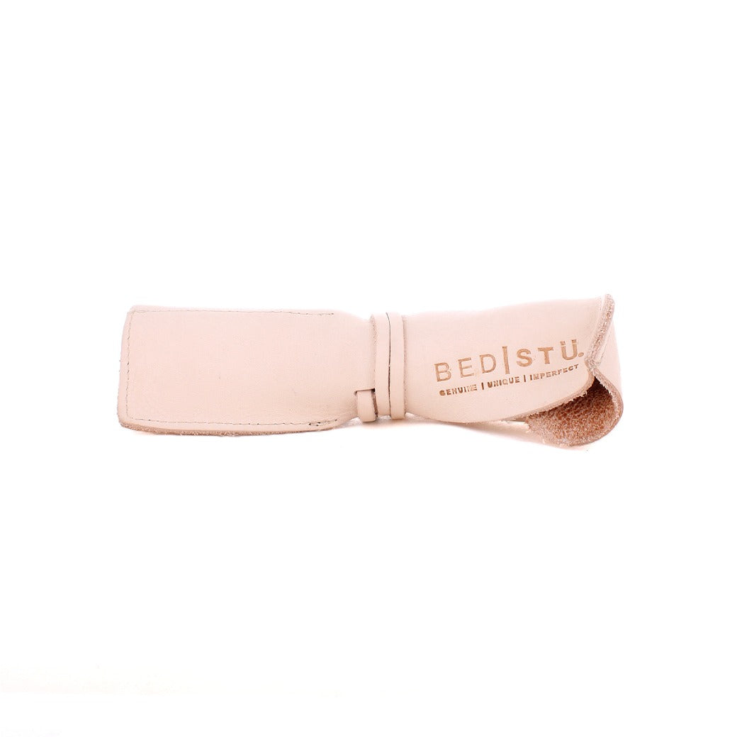 A beige leather wrap with the text "Bed Stu" followed by "Genuine. Unique. Imperfect." printed on it, crafted from the finest materials at our Leather Shoppe.