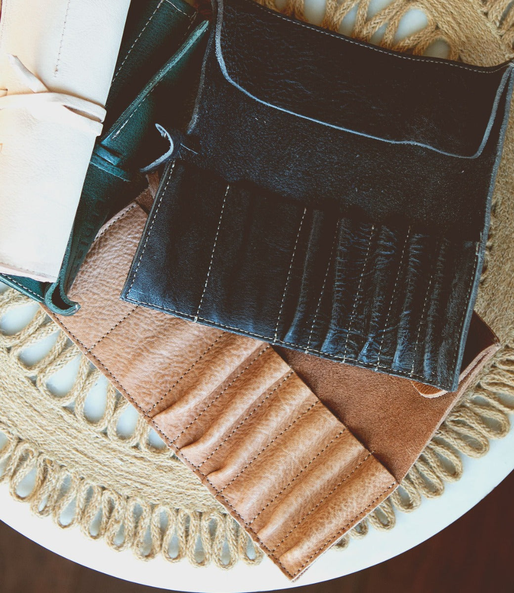 Several Prepped Leather Wraps in different colors are placed on a round, woven, off-white table mat, showcasing the fine craftsmanship of Bed Stu.