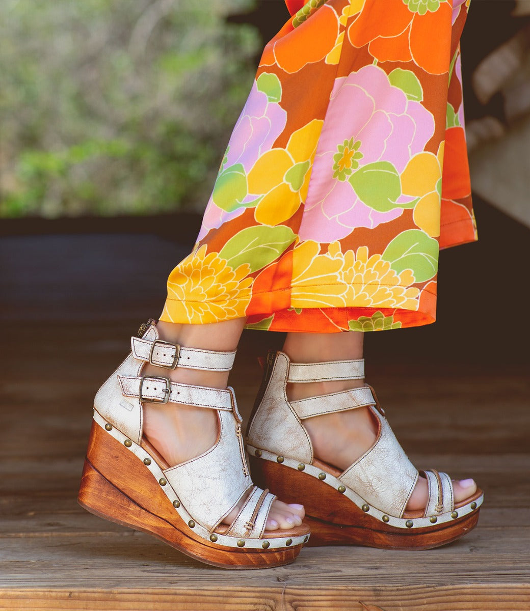 A woman wearing a floral dress and Bed Stu Princess wedge sandals.