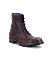 A single Protege Trek boot by Bed Stu, featuring red and black leather lace-up details and a rugged Vibram outsole, is shown against a white background, epitomizing the combat style boot aesthetic.