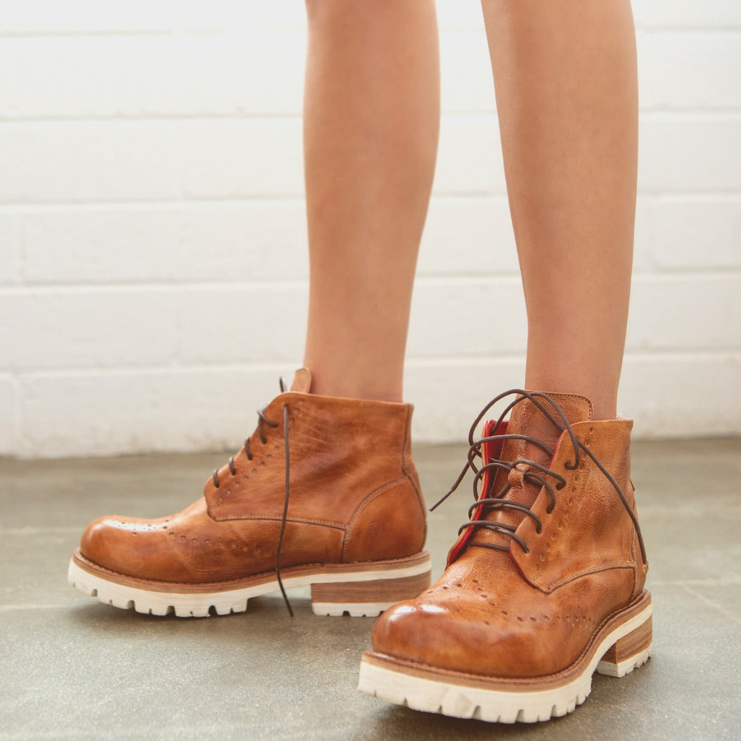 A woman wearing a pair of Bed Stu Quatro III brown lace up boots.
