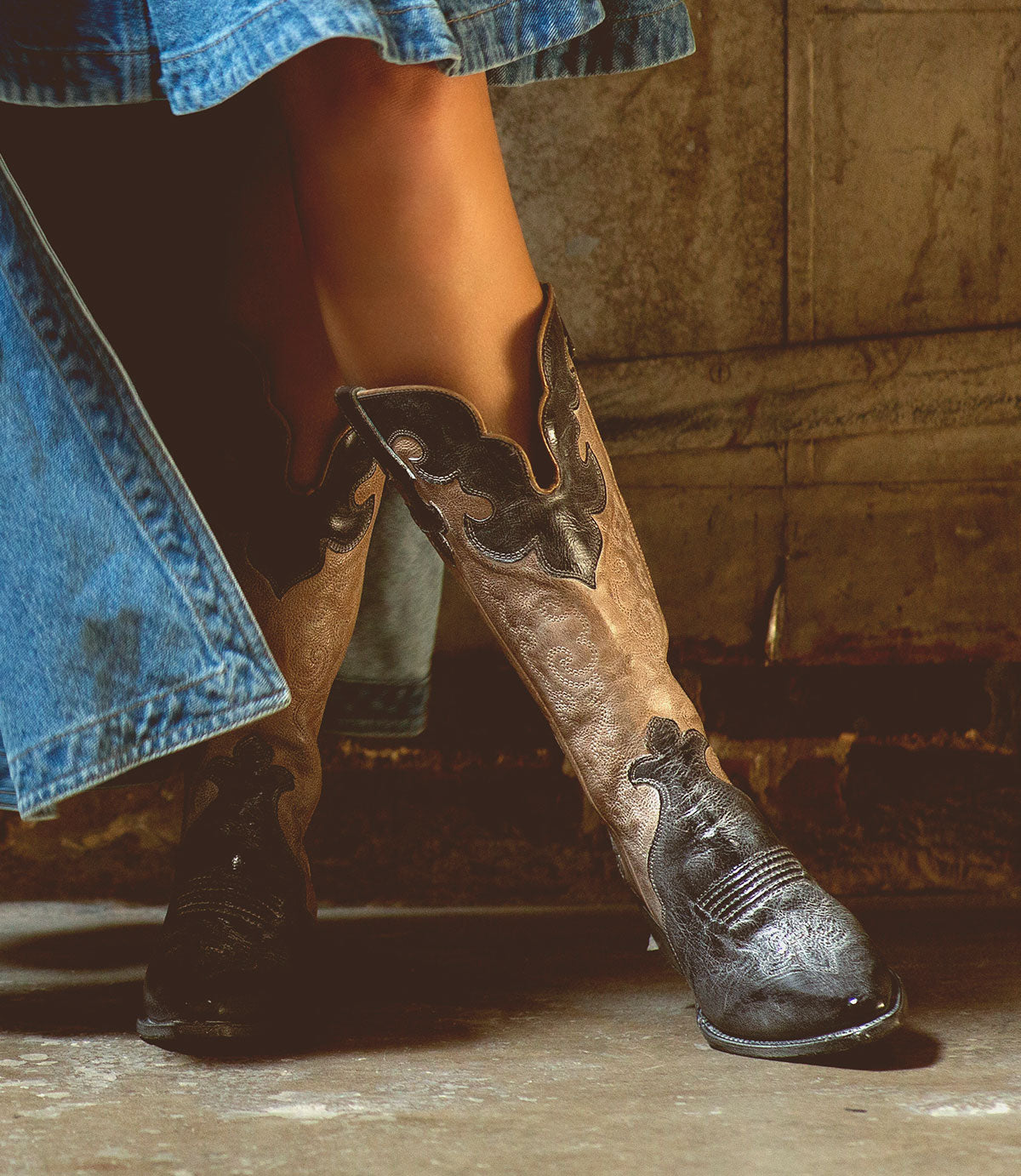 A fashionable Bed Stu Queen wearing tall cowboy boots and a denim skirt.