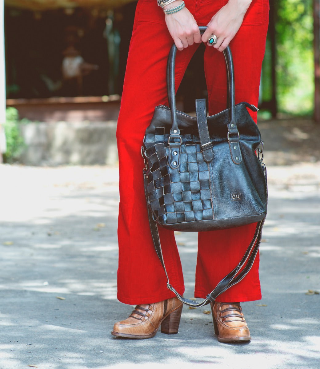 A woman in red pants holding a Bed Stu Rachel handbag.