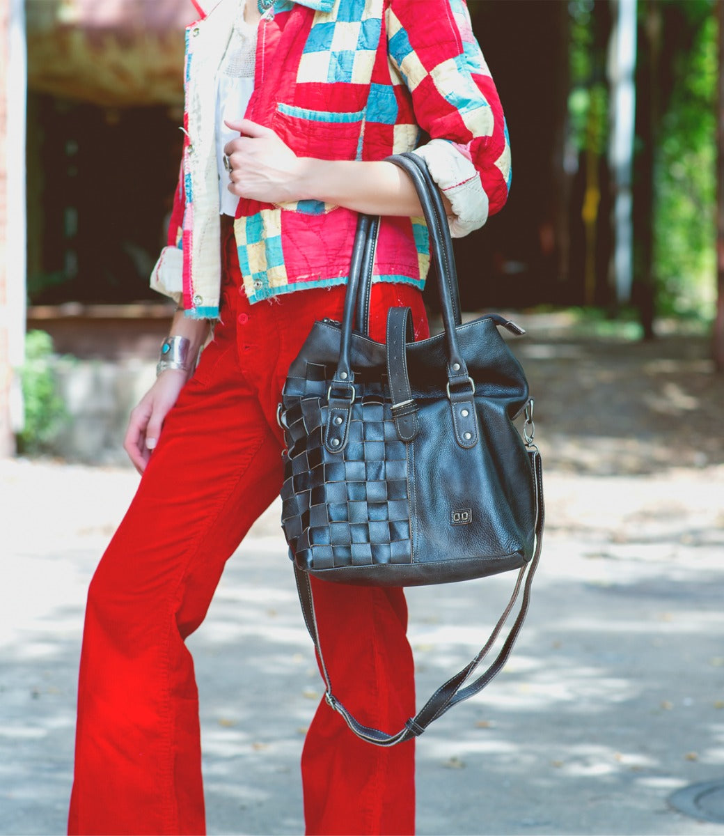 A woman wearing red pants holding a Rachel bag from Bed Stu.