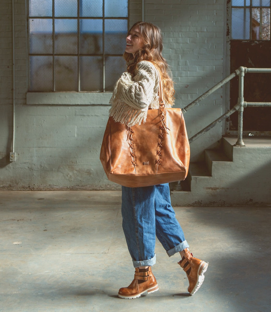 A woman carrying a Bed Stu Rebekah tan leather tote.