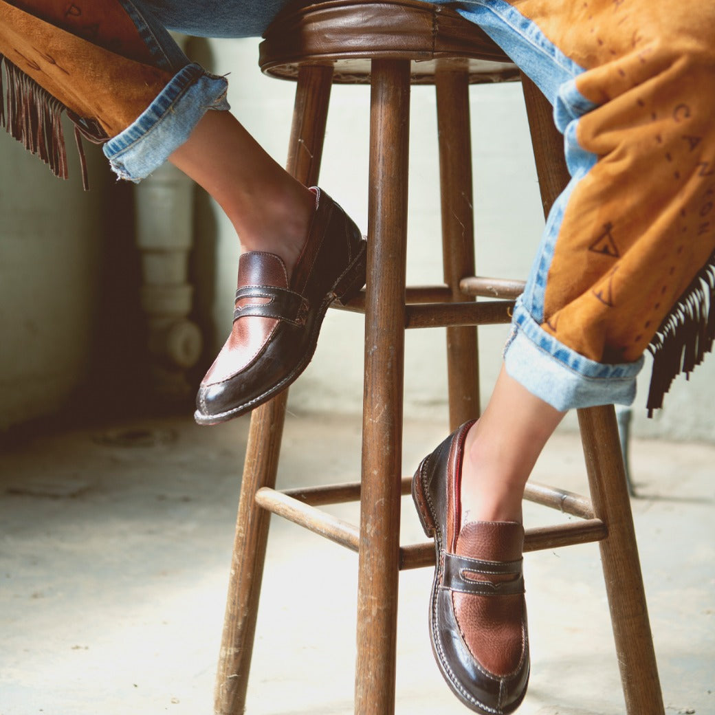 A person sitting on a stool wearing a pair of Reina by Bed Stu boots.