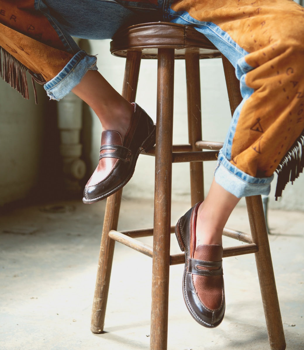 A person sitting on a stool wearing a pair of Reina by Bed Stu boots.