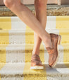 A woman wearing a Bed Stu Reina III loafer standing on a yellow and white striped staircase.