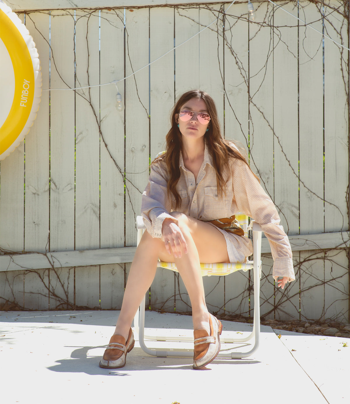 A woman sitting on a chair in front of a yellow sign, holding the Reina by Bed Stu.