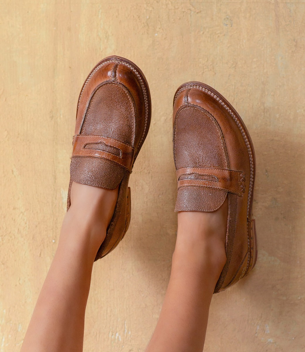 The legs of a woman wearing Bed Stu Reina brown loafers.