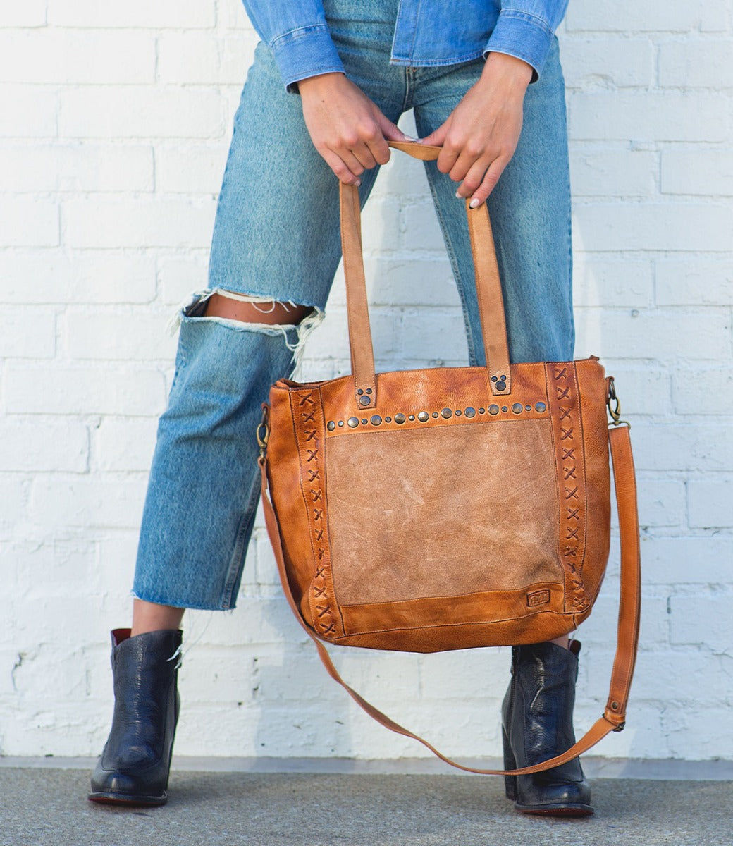 A woman holding a Bed Stu Renata LTC tote bag.