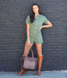 A woman wearing a green outfit and a brown Bed Stu Renata LTC leather bag.