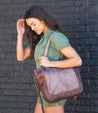 A woman wearing green shorts and a brown Bed Stu Renata LTC leather bag.
