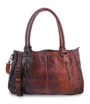 The Rockababy by Bed Stu is a leather handbag featuring comfortable padded shoulder straps, a front pocket tied with leather strings, and a detachable, adjustable strap. The bag showcases stitch detailing along the edges and includes a small leather tag.