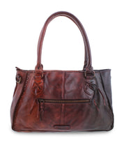 The Rockababy by Bed Stu is a brown leather handbag featuring two handles, a front zipper pocket, decorative stitching accents, and a versatile crossbody strap.