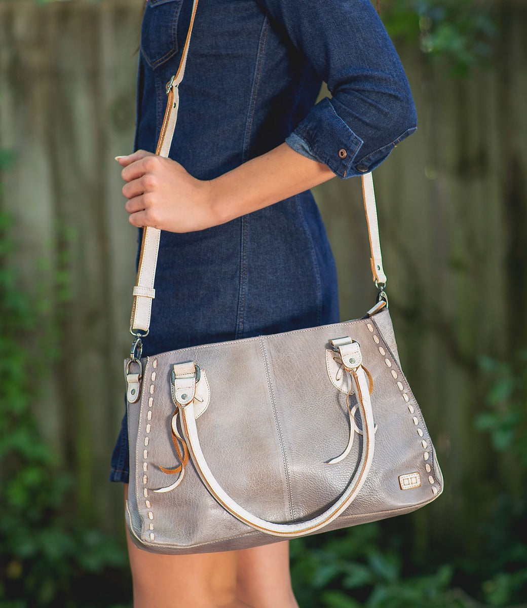 A woman in a denim dress holding a Bed Stu Rockababy bag.