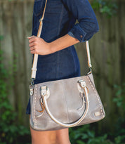 A woman in a denim dress holding a Bed Stu Rockababy bag.