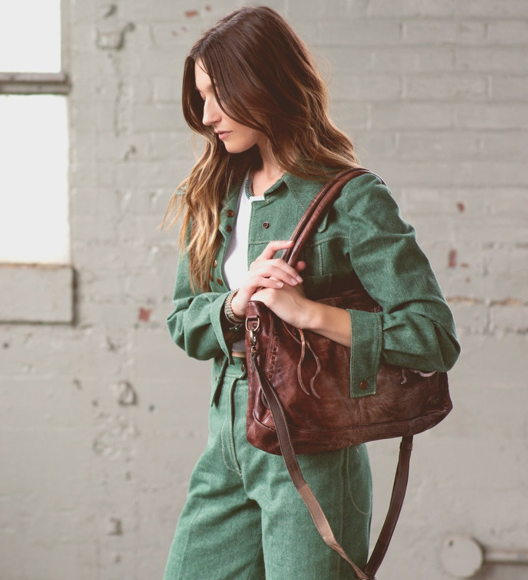 A woman in green jumpsuit holding a Bed Stu Rockababy bag.