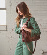 A woman in green jumpsuit holding a Bed Stu Rockababy bag.