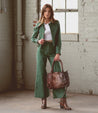 A woman wearing green corduroy pants and a Bed Stu Rockababy leather bag.