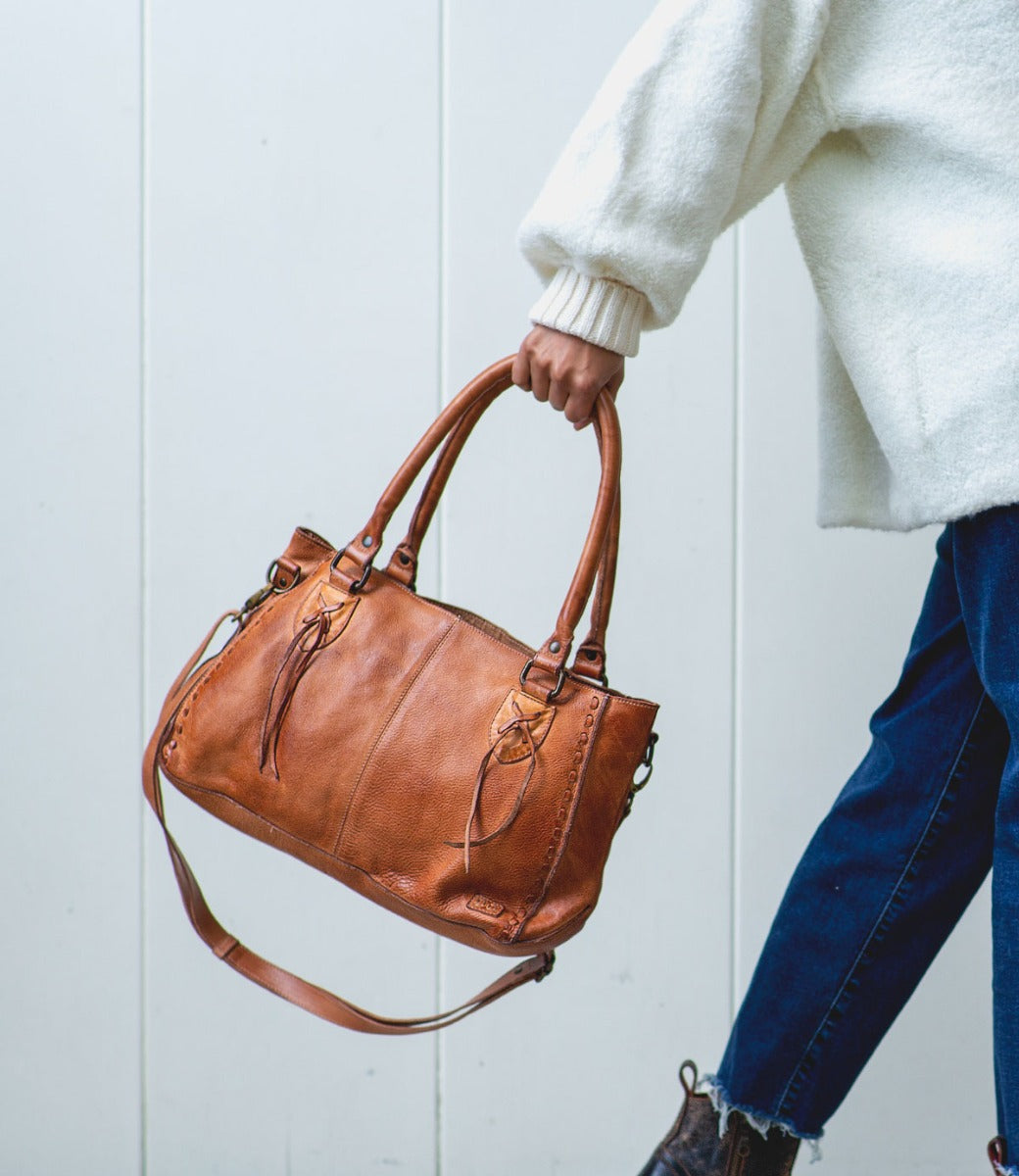 A woman carrying a Rockababy tan leather handbag by Bed Stu.