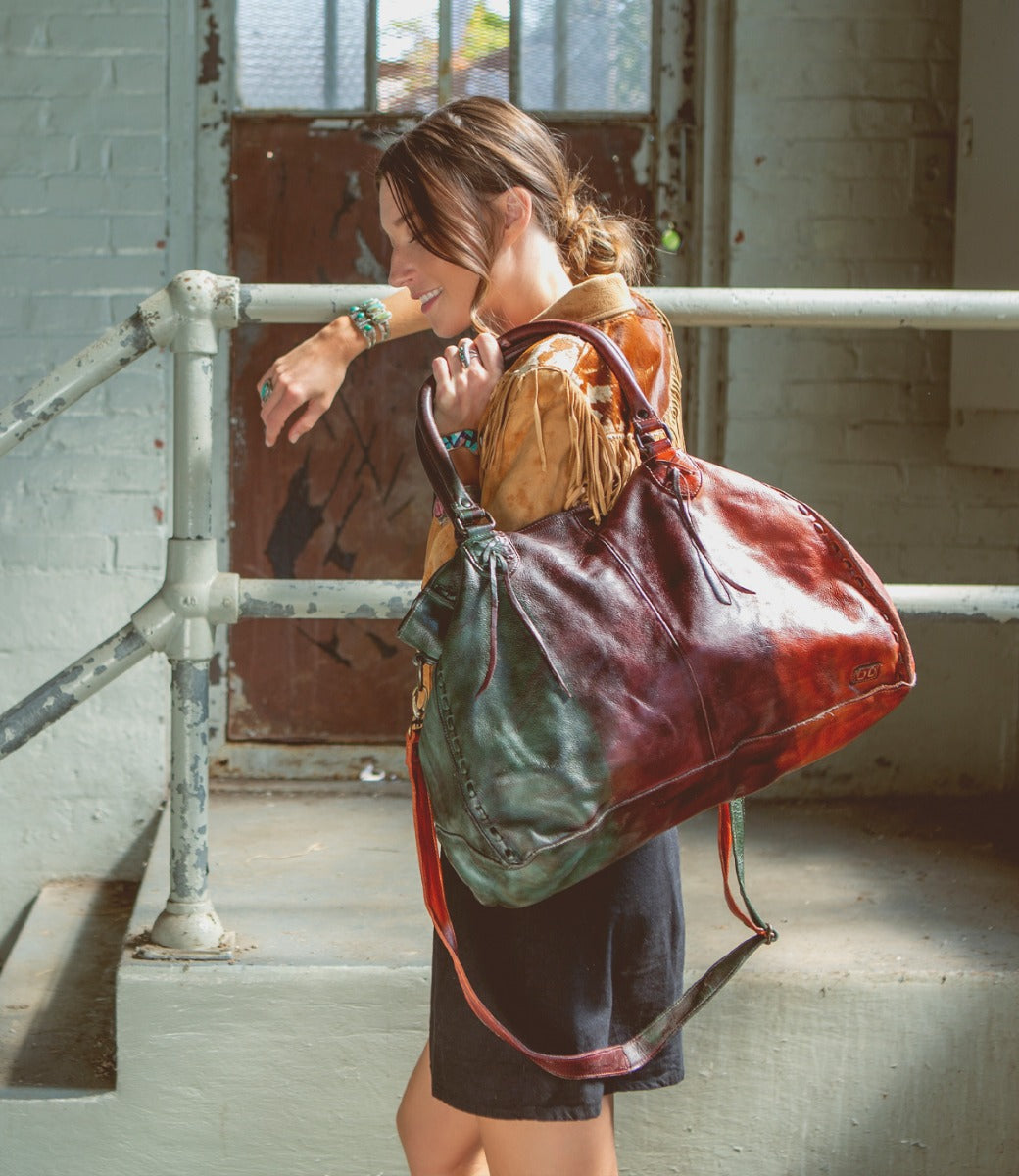 A woman is holding a colorful Rockaway leather bag by Bed Stu.