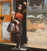 A woman holding a Rockaway bag in front of a silver bus by Bed Stu.