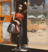 A woman holding a Rockaway bag in front of a silver bus by Bed Stu.