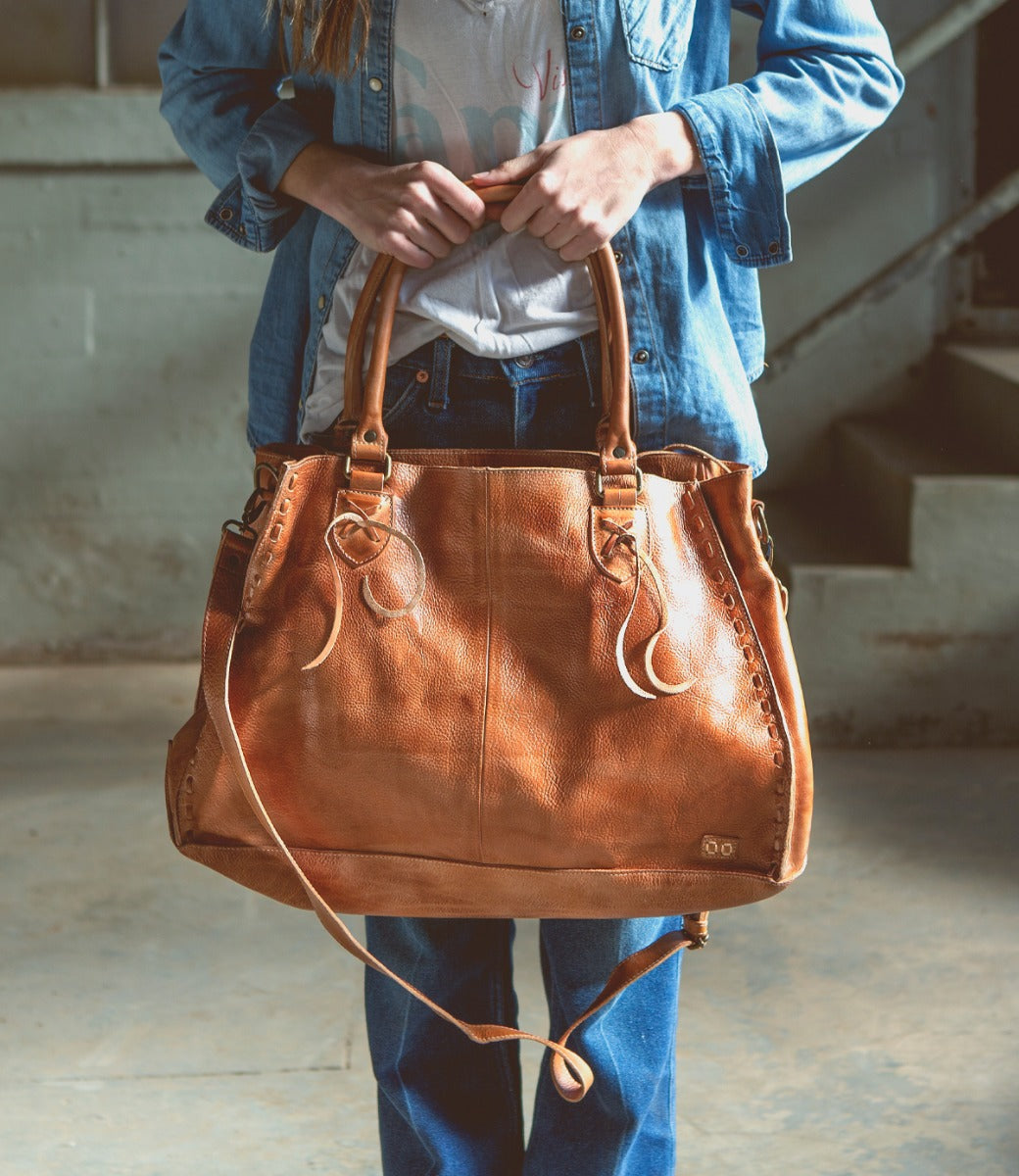 A woman holding a Rockaway leather bag by Bed Stu.