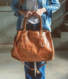 A woman holding a Rockaway leather bag by Bed Stu.