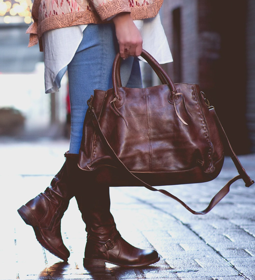 A woman carrying a Rockaway handbag by Bed Stu on a sidewalk.