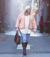 A plus size woman walking down an alley wearing a pink floral Bed Stu Rockaway jacket and boots.