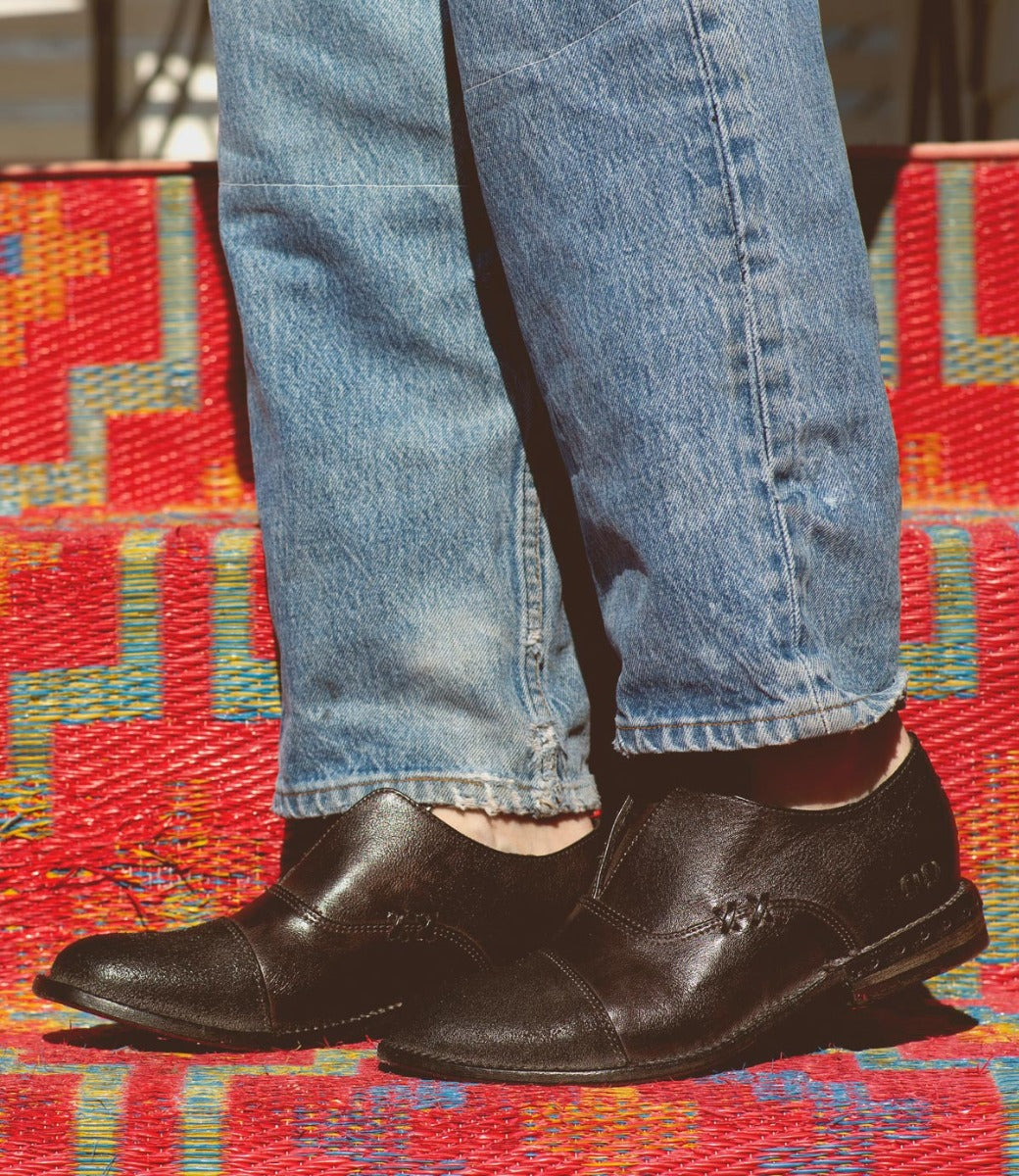 A pair of black Bed Stu Rose shoes on a person's feet.