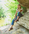 A Bed Stu woman sitting on a rock holding a Rose.