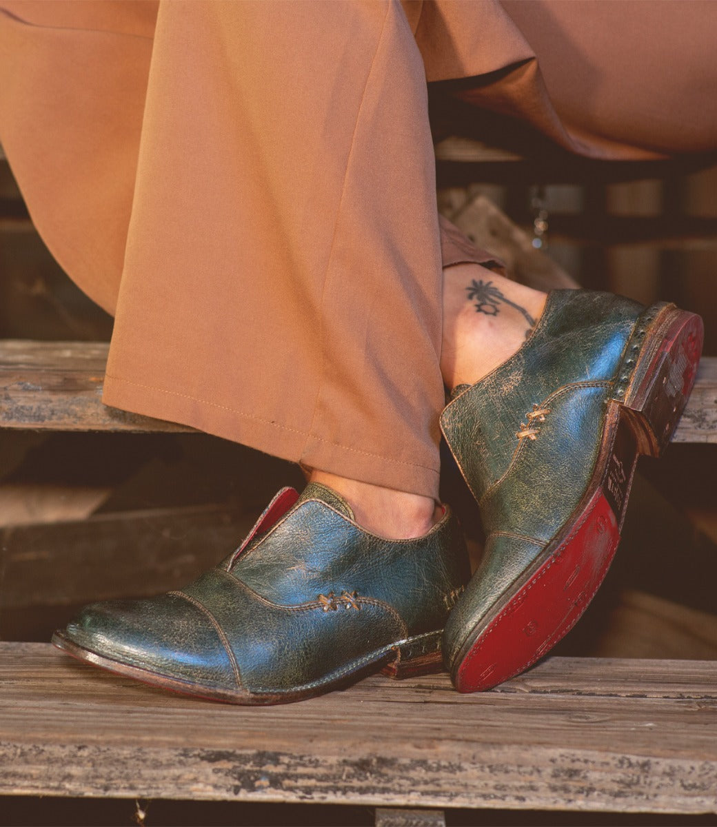 A person wearing a pair of Bed Stu Rose green leather shoes.