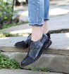 A woman in jeans and black Bed Stu Rose shoes standing on steps.