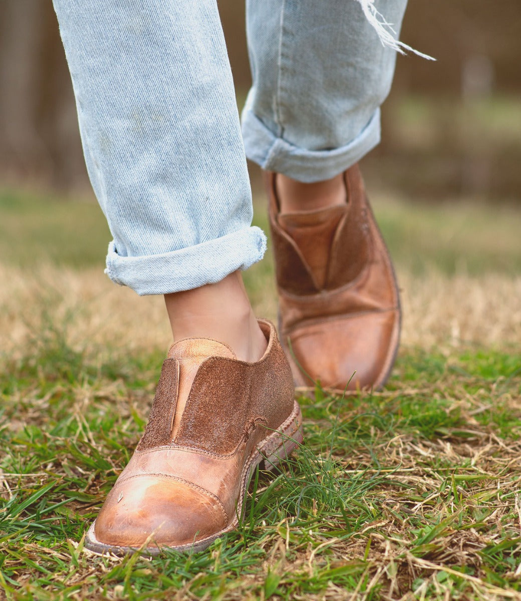 A woman wearing a pair of Bed Stu Rose shoes walking in the grass.