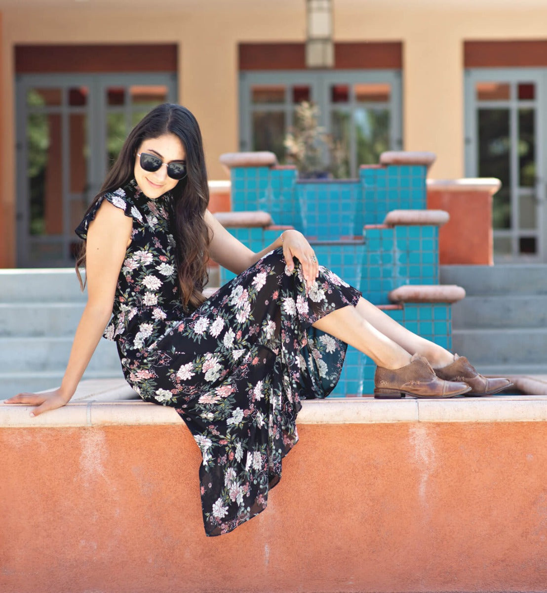 A woman in a floral dress sitting on a Bed Stu Rose wall.