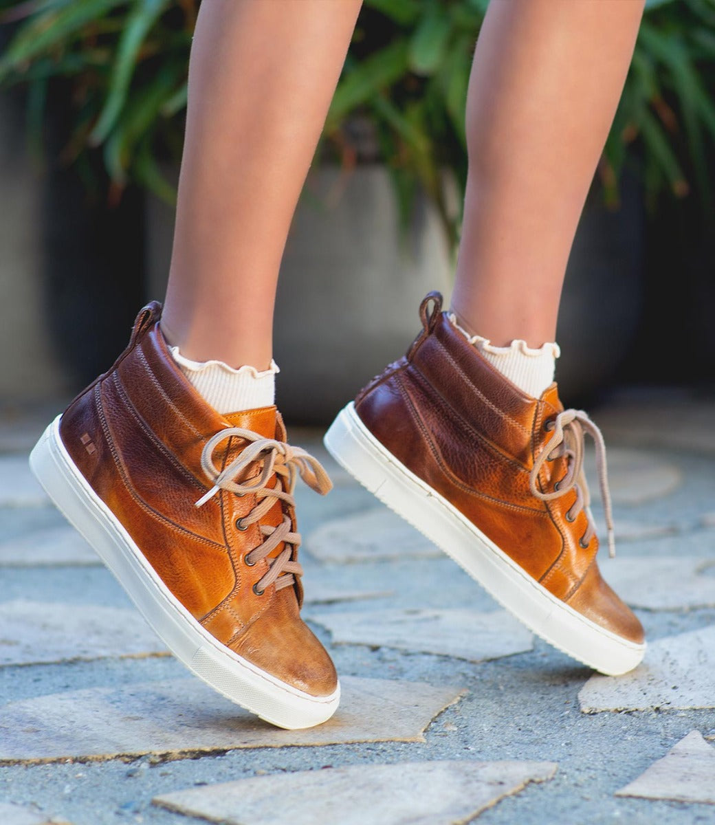 A woman wearing a Rossela by Bed Stu tan leather high top sneaker.