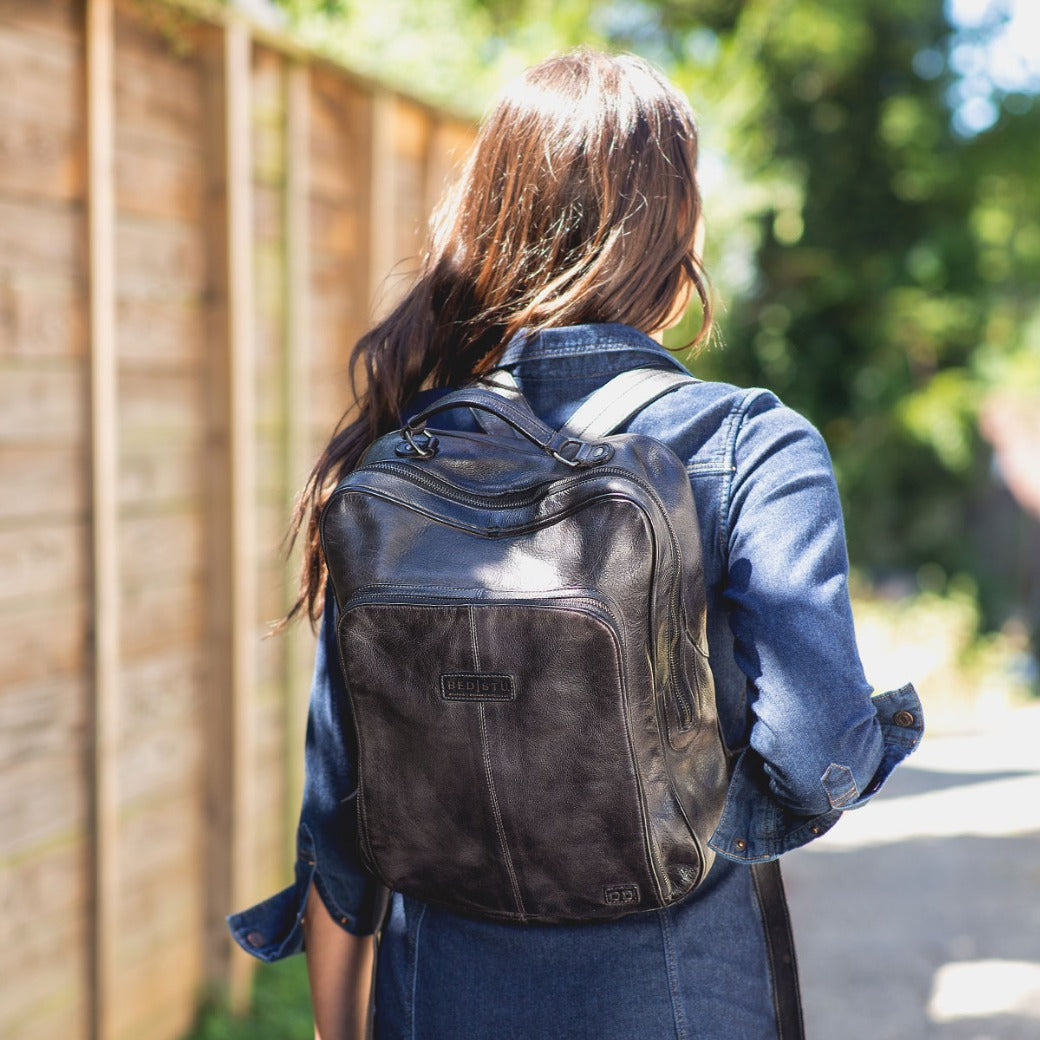A woman walking down the street with a Bed Stu Rozes black leather backpack.