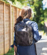 A woman walking down the street with a Bed Stu Rozes black leather backpack.