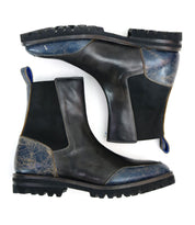 Salatiel boots by Bed Stu, featuring a black Chelsea design with textured blue accents and a leather footbed, are highlighted by their rugged black soles and displayed side by side on a pristine white background.