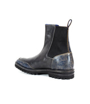 A single Salatiel Chelsea boot by Bed Stu, featuring a black and dark blue leather design with a textured sole and rugged craftsmanship, viewed from the side against a white background.