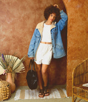 A woman in shorts and denim jacket holding a Saray bag from Bed Stu.