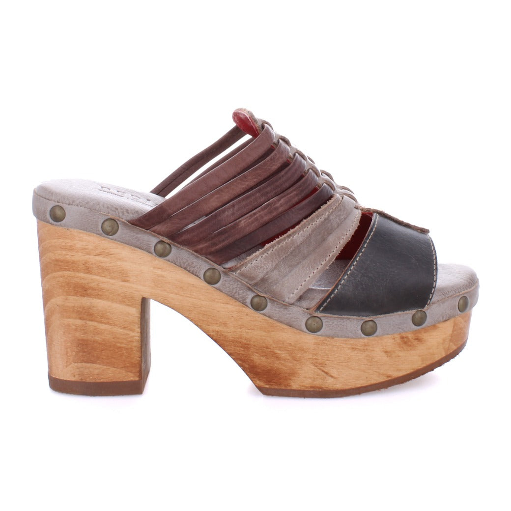 The Shantel by Bed|Stü is a cheery clog sandal showcasing a wooden platform sole, studded trim, and multi-colored leather straps in brown, gray, and black. Finished with a cushioned leather insole for added comfort.