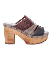 The Shantel by Bed|Stü is a cheery clog sandal showcasing a wooden platform sole, studded trim, and multi-colored leather straps in brown, gray, and black. Finished with a cushioned leather insole for added comfort.