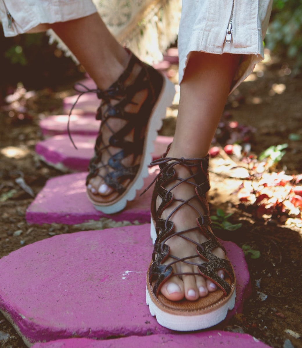 A woman's feet walking on a Bed Stu Shirin II stone path.