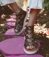 A woman's feet walking on a Bed Stu Shirin II stone path.